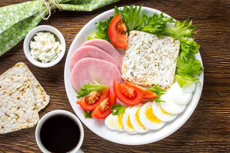Diet breakfast, ham, tomatoes, boiled egg, crisp bread, soft cheese, green salad, coffee, tasty foodの写真素材