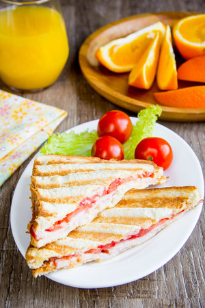 Grilled sandwich, toast with cheese, ham and tomato, delicious European Breakfast with orange juiceの写真素材