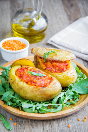 Whole potatoes with skins stuffed with vegetable tomato stew with red lentil, delicious vegetarian dishの写真素材