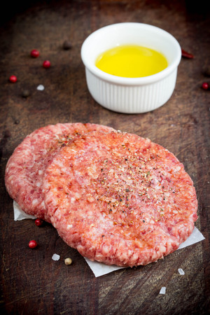 Raw Burger cutlet with herbs, preparation for roasting, cooking, home cooking in rustic styleの写真素材