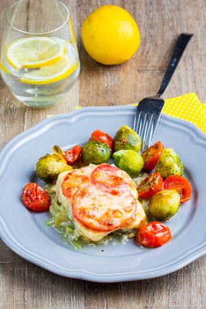 Fish baked with cheese and tomatoes, Brussels sprouts and cherry tomatoesの写真素材