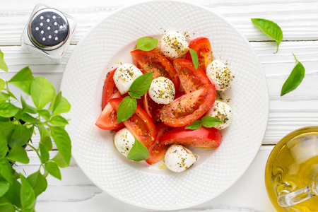 Italian fresh tomato Caprese salad, mozzarella and Basil, delicious light summer snackの写真素材