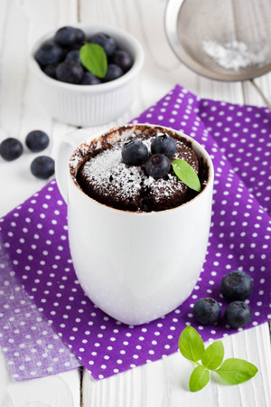 Chocolate cake in a mug with blueberry and powdered sugar, delicious summer dessertの写真素材