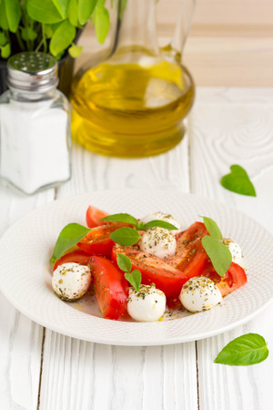 Italian fresh tomato Caprese salad, mozzarella and Basil, delicious light summer snackの写真素材