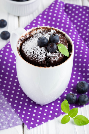 Chocolate cake in a mug with blueberry and powdered sugar, delicious summer dessertの写真素材