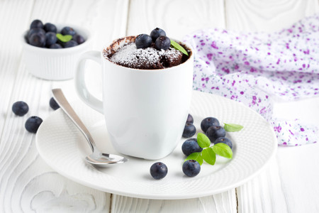 Chocolate cake in a mug with blueberry and powdered sugar, delicious summer dessertの写真素材