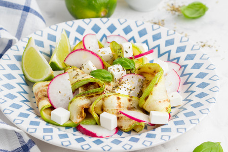 Fresh healthy salad with grilled zucchini, radish, feta, lime, tasty summer snackの写真素材