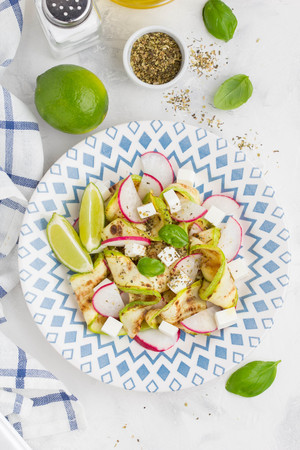 Fresh healthy salad with grilled zucchini, radish, feta, lime, tasty summer snackの写真素材