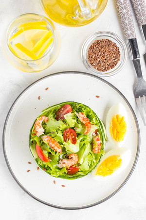 Fresh salad with crayfish necks, lettuce, cherry tomatoes, egg in a ring of cucumbersの写真素材