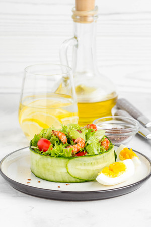 Fresh salad with crayfish necks, lettuce, cherry tomatoes, egg in a ring of cucumbersの写真素材