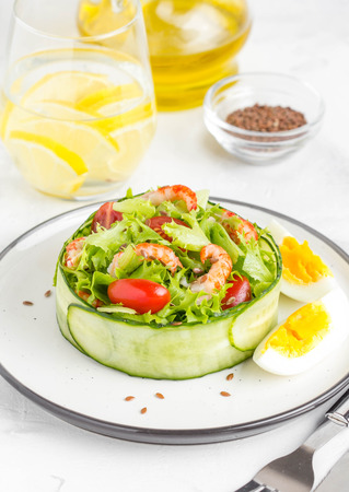 Fresh salad with crayfish necks, lettuce, cherry tomatoes, egg in a ring of cucumbersの写真素材