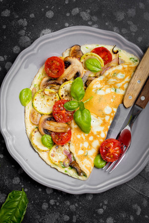 Thin rolled omelet with fried vegetables, zucchini, tomato, onion, mushrooms, delicious healthy Breakfast,の写真素材