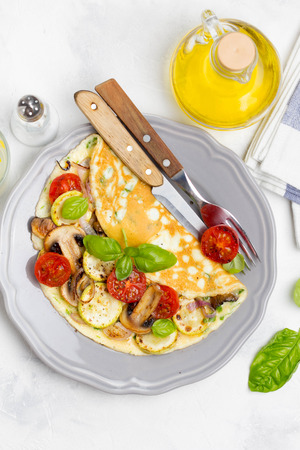 Thin rolled omelet with fried vegetables, zucchini, tomato, onion, mushrooms, delicious healthy Breakfast,の写真素材