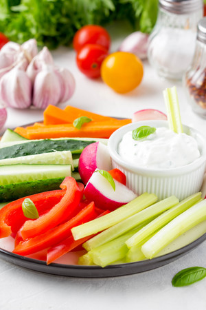 Tasty vegetable sticks of cucumber, pepper, carrots, celery and radishes with white sauce of sour cream, yogurt, herbs.の写真素材