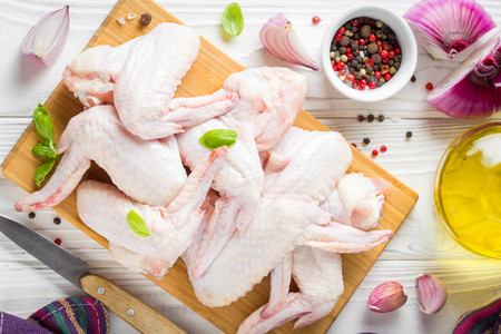 Raw chicken wings on a cutting board. Ingredients for cooking, spices, onion, oil and garlicの写真素材