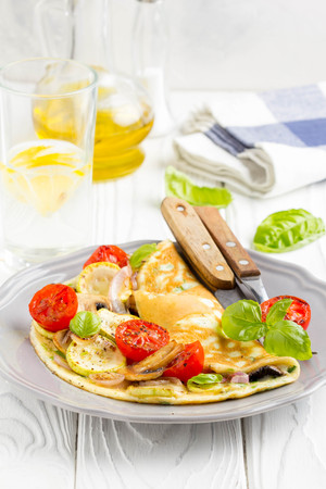 Thin rolled omelet with fried vegetables, zucchini, tomato, onion, mushrooms, delicious healthy Breakfast,の写真素材