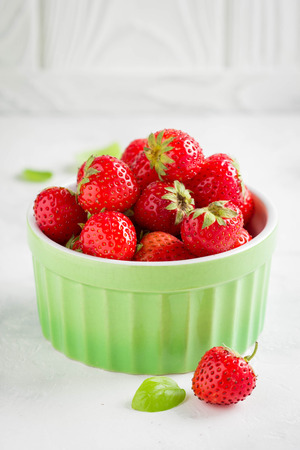 Small strawberry in green cup, fresh juicy summer berry on light background, home harvest, gardenの写真素材