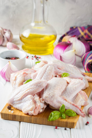 Raw chicken wings on a cutting board. Ingredients for cooking, spices, onion, oil and garlicの写真素材
