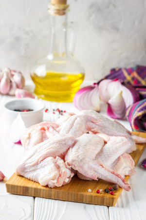 Raw chicken wings on a cutting board. Ingredients for cooking, spices, onion, oil and garlicの写真素材