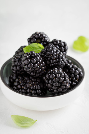 Blackberries in a cup, fresh juicy summer berry on a light background, home harvest, gardenの写真素材