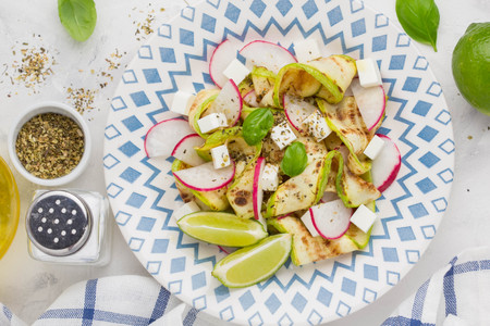 Fresh healthy salad with grilled zucchini, radish, feta, lime, tasty summer snackの写真素材