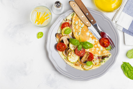 Thin rolled omelet with fried vegetables, zucchini, tomato, onion, mushrooms, delicious healthy Breakfast,の写真素材