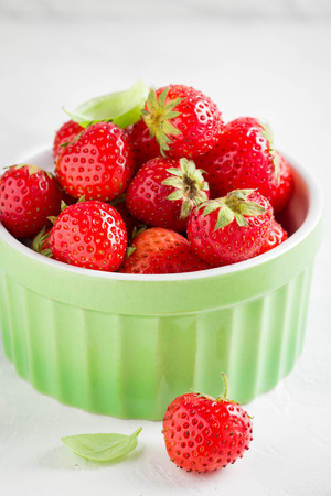 Small strawberry in green cup, fresh juicy summer berry on light background, home harvest, gardenの写真素材