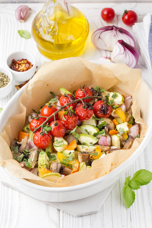 Baked vegetables with mushrooms in white. Zucchini, cherry tomatoes on a branch, red onions, bell peppers and garlic. Delicious garnish, vegetarian food, healthy dietの写真素材