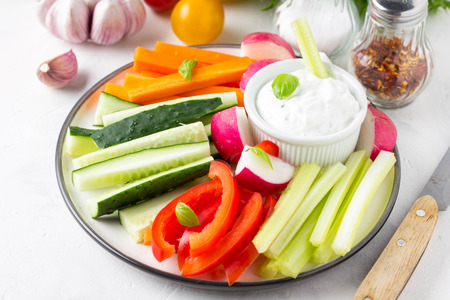 Tasty vegetable sticks of cucumber, pepper, carrots, celery and radishes with white sauce of sour cream, yogurt, herbs.の写真素材