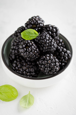 Blackberries in a cup, fresh juicy summer berry on a light background, home harvest, gardenの写真素材