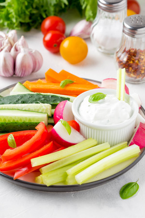 Tasty vegetable sticks of cucumber, pepper, carrots, celery and radishes with white sauce of sour cream, yogurt, herbs.の写真素材