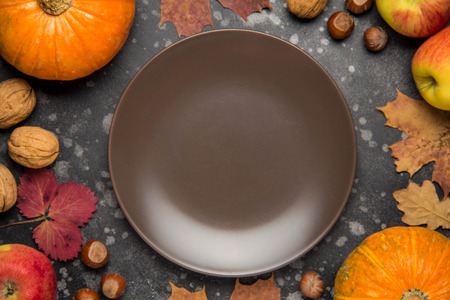 Apples,pumpkins, hazelnut, walnut and fallen leaves on dark background. Copy space for text, top view. Empty dark plateの写真素材
