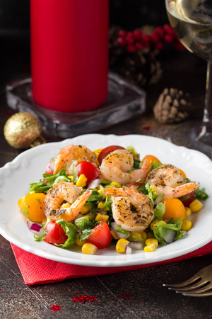 Salad with corn, fried shrimp, cherry tomatoes, red onions and lettuce on  white plate.の写真素材