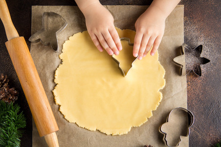 Children is cooking Christmas cookies, cut the dough with cookie cutter, family traditions, delicious sweet holiday foodの写真素材