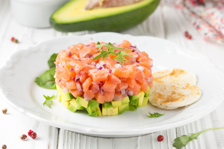 Salmon tartar with red onion, avocado, arugula and bread toast.の写真素材