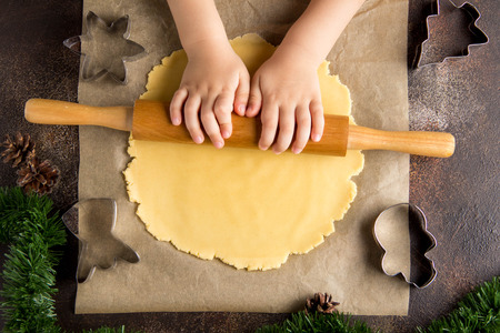 Children is cooking Christmas cookies, roll out the dough, a family tradition, tasty sweet holiday foodの写真素材