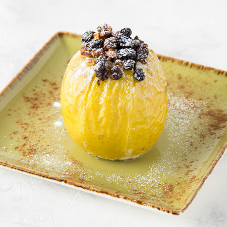 Baked stuffed yellow apple with caramel, nuts and dried fruitsの写真素材