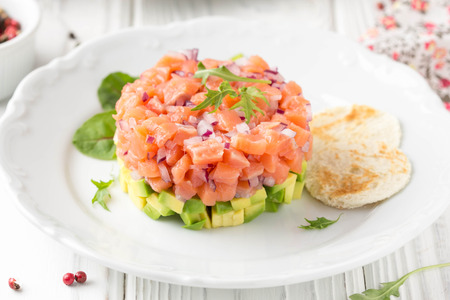 Salmon tartar with red onion, avocado, arugula and bread toast.の写真素材