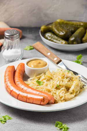 Stewed white cabbage with two long fried sausages, mustard and pickled cucumbers.の写真素材