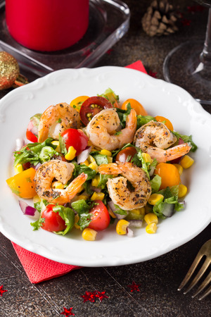 Salad with corn, fried shrimp, cherry tomatoes, red onions and lettuce on  white plate.の写真素材