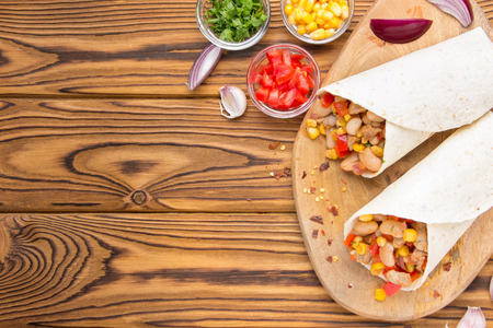 Burrito in tartilla with meat, vegetables, white beans, red pepper, corn. Delicious lunch, Mexican food, homemade snackの写真素材