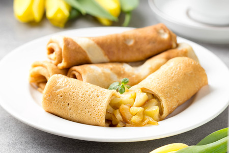 Thin pancakes (crepes) with apple filling, stuffed rolls, Russian traditional food for maslenitsa, French dessert, breakfast with tulips on mother's dayの写真素材