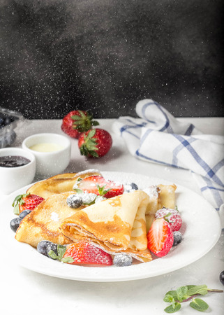 Thin pancakes with strawberries and blueberries, jam, condensed milk, delicious Breakfast. Russian traditional dessert for Shrovetide celebration (maslenitsa). French crepesの写真素材