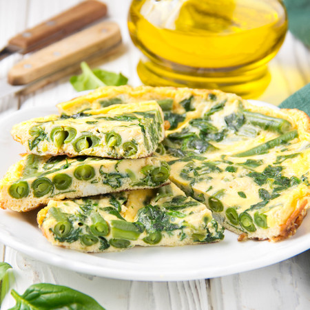 Omelet with spinach and green beans, healthy food. Egg and milk Frittata, delicious Breakfast on white wooden backgroundの写真素材