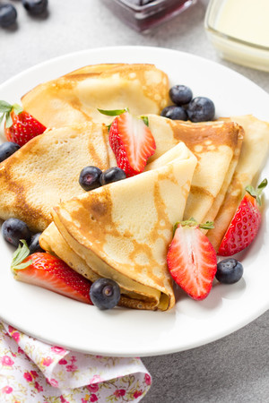 Thin pancakes with strawberries and blueberries, jam, condensed milk, delicious Breakfast. Russian traditional dessert for Shrovetide celebration (maslenitsa). French crepesの写真素材