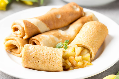 Thin pancakes (crepes) with apple filling, stuffed rolls, Russian traditional food for maslenitsa, French dessert, breakfast with tulips on mother's dayの写真素材