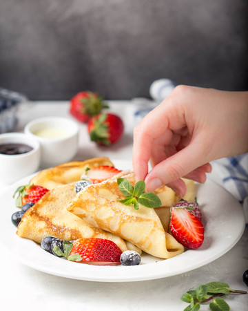 Thin pancakes with strawberries and blueberries, jam, condensed milk, delicious Breakfast. Russian traditional dessert for Shrovetide celebration (maslenitsa). French crepesの写真素材