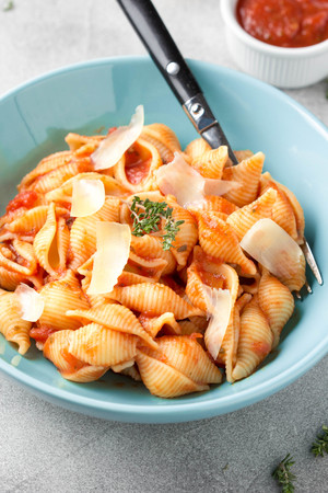 Pasta conchiglioni (conchiglie, shells) with tomato sauce, Parmesan cheese and thyme in a blue plate on a gray background. Delicious healthy vegetarian food, Italian cuisineの写真素材