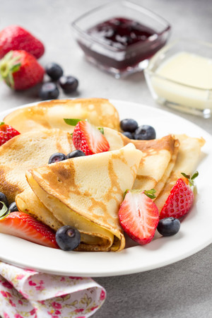 Thin pancakes with strawberries and blueberries, jam, condensed milk, delicious Breakfast. Russian traditional dessert for Shrovetide celebration (maslenitsa). French crepesの写真素材