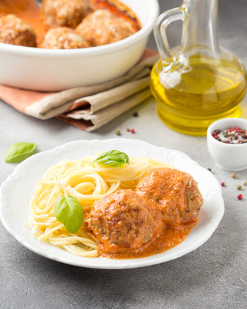 Meatballs in tomato sauce with cheese and pasta spaghetti, baked pork and beef cutlets in baking dish. Delicious homemade foodの写真素材